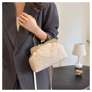 Detail of cream vintage shell bag with embossed floral texture and gold metal handle