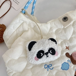 Dettaglio borsa cuore trapuntata bianca con ricamo e ciondolo panda in peluche