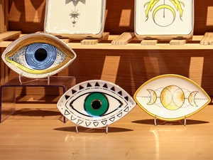 Detailed view of ceramic evil eye and moon phase jewelry trays on a wooden surface
