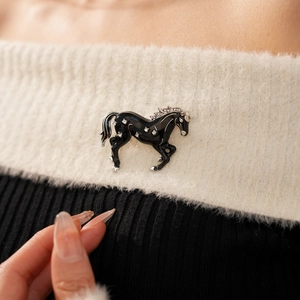 Close-up of a vintage horse brooch with black enamel and diamonds on a plush fabric
