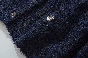 Dettaglio macro del tessuto tweed blu scuro con bottoni in metallo argentato
