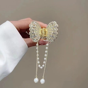 Close-up of golden butterfly hair claw with tassel chains and elegant faux pearls
