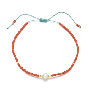 Detail of bohemian orange beaded bracelet with freshwater pearl and adjustable blue cord