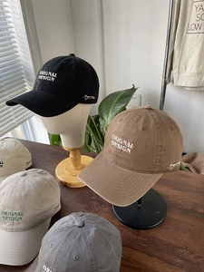 Detailed embroidery on cotton baseball caps displayed on wooden stands in natural light