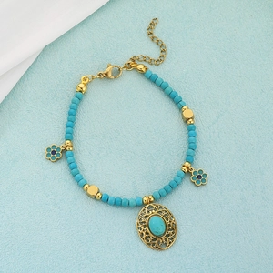 Detail of beaded turquoise bracelet with golden filigree pendant and flower charms