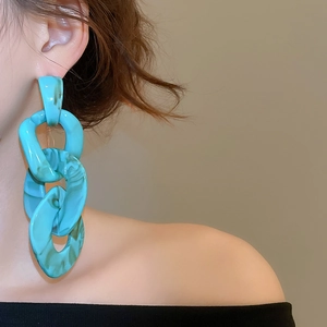 Close-up of blue marble acrylic chain drop earrings worn by a female model