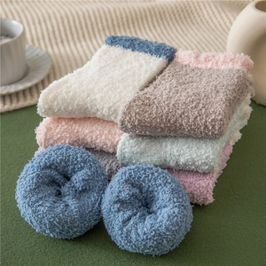 Pile of colorful coral fleece socks in soft pastel tones showing plush warm texture