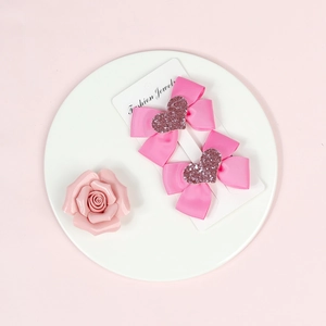 Pair of pink grosgrain ribbon hair bows with glitter hearts on white display card