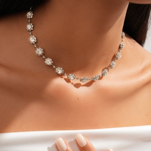 Detailed view of a silver floral choker with sparkling crystals on a model's neck