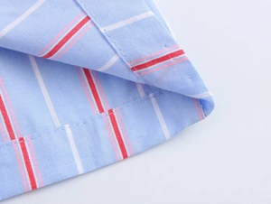 Macro view of blue striped poplin shirt hem showing precise stitching and fabric texture