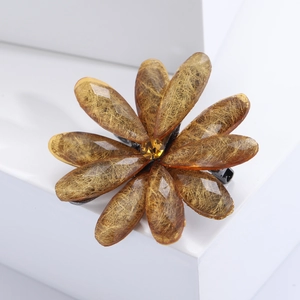 Detailed close-up of amber flower brooch with gold silk texture and yellow crystal center
