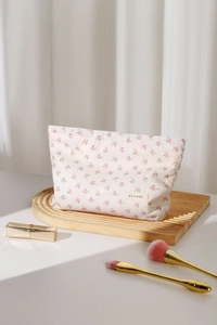 Détail de la trousse de maquillage florale avec étiquette H & R sur un support en bois