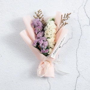 Dettaglio di bouquet di fiori secchi viola e bianchi con un tag messaggio di felicità