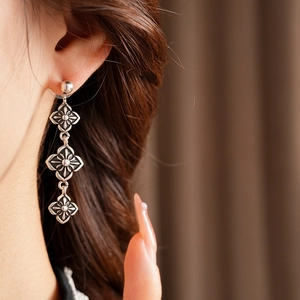 Close-up of vintage silver cross flower long drop earrings worn by a female model