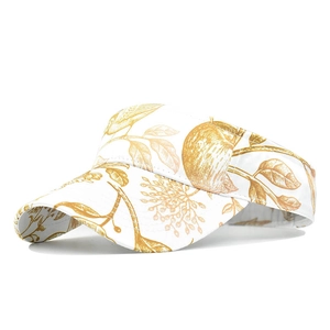 Detail of white sun visor hat with gold floral pattern for outdoor sun protection