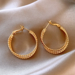 Detailed close-up of triple-layered gold spiral earrings on soft grey silk fabric