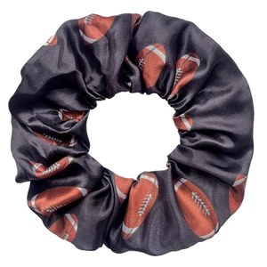 Détail d'un chouchou en satin noir avec motifs de football américain et texture plissée