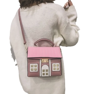 Sac à main en forme de maison rose avec bandoulière porté par un mannequin pour la taille