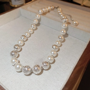 Detail of elegant pearl necklace with silver textured metal beads on a jewelry tray