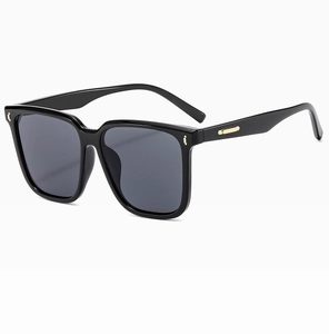 Detail view of large square sunglasses with glossy black frame and gold metal accents