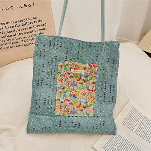 Detail of blue denim tote bag with green sequins and a floral fabric pocket design