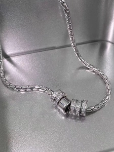 Macro shot of silver titanium steel woven chain with five sparkling crystal paved cylinders