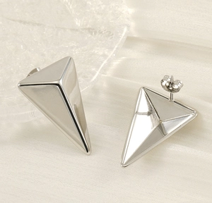 Macro shot of silver triangular stud earrings with butterfly backs on a glass tray