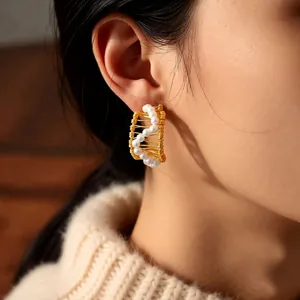 Elegant 18k gold plated C-shaped pearl hoop earrings worn by a model in warm lighting