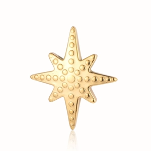 Detail of gold-colored octagonal star pendant with textured surface on white background