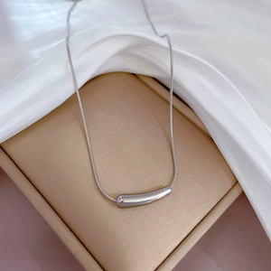 Details einer silbernen Schlangenkette mit gebogenem Metallanhänger auf einer Box