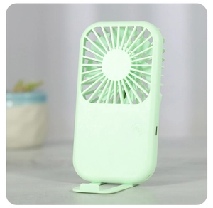 Detail of portable mint green mini fan with foldable stand on a desk background
