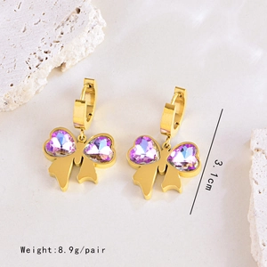 Détail de boucles d'oreilles cœur papillon dorées avec cristaux violets et mesures