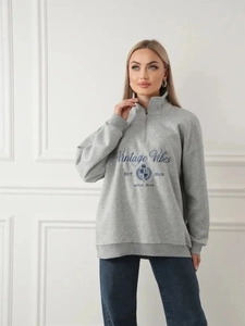 Detail eines grauen Sweatshirts mit halbem Reißverschluss und Vintage-Buchstabendruck