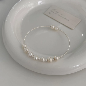 Macro detail of natural freshwater pearls on minimalist silver-plated open bangle