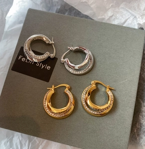 Detail of gold and silver double-layered twisted hoop earrings with sparkling cubic zirconia