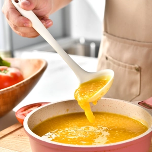 Heat-resistant white silicone soup ladle scooping porridge from a cooking pot