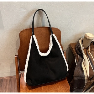 Detail of black suede tote bag with white plush trim displayed on a vintage chair