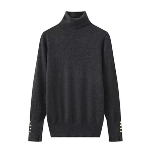Detail view of dark grey knit sweater showing golden decorative buttons on cuffs