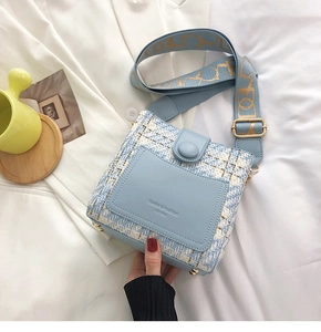 Detail of tweed crossbody bucket bag with blue-white weave and wide jacquard strap