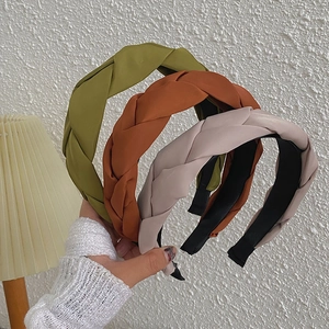 Close-up of olive, brick red and dusty pink braided headbands with fabric texture