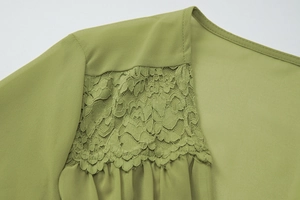 Détail de l'épaule en mousseline vert olive avec dentelle délicate et textures fines