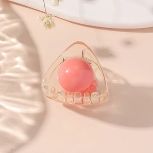 Dettaglio di un ciondolo a sfera rosa in una mini clip per capelli in acrilico