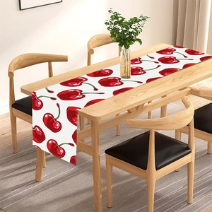 Linen table runner with red cherry print on a wooden dining table in a modern setting