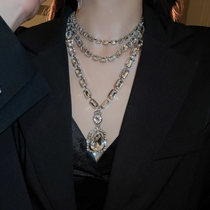 Detailed view of layered silver necklace with rectangle crystals and teardrop pendant