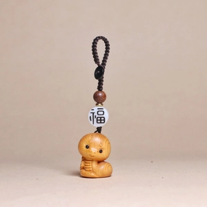 Detailed wood texture of a carved zodiac snake pendant with a lucky ceramic bead