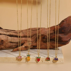 Gros plan de colliers dorés avec pendentifs méduse et fruits en zircone colorée