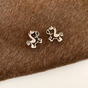Close-up of golden horse-shaped earrings with minimalist hollow outline design