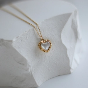 Macro shot of vintage gold heart pendant with shell inlay and hollow floral relief border