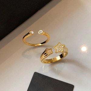 Adjustable gold plated star ring set with sparkling cubic zirconia on a beige background