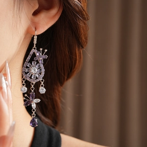 Detailed close-up of a zircon butterfly and flower drop earring worn by a model
